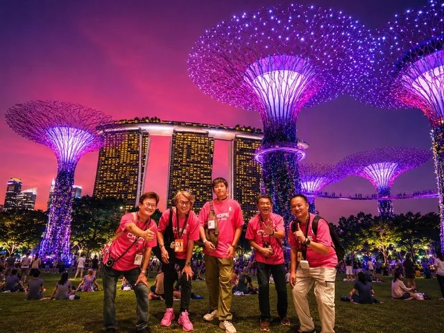 Group of people posing in front of illuminated Supertrees and Marina Bay Sands