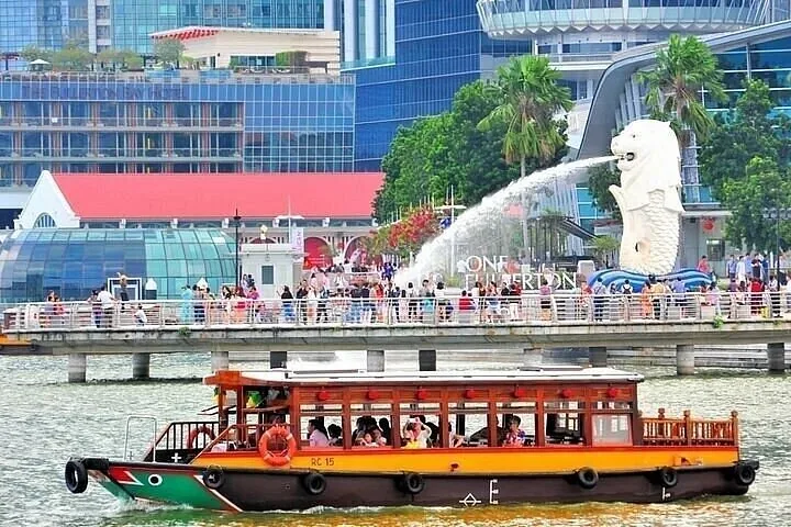 Tour boat cruising past the Merlion statue in Singapore during daytime